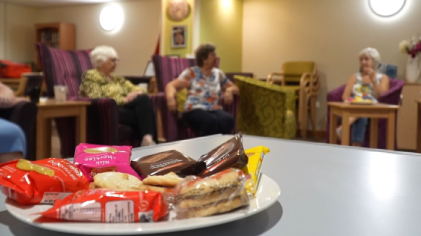 A table with biscuits in the foreground and some people in the background
